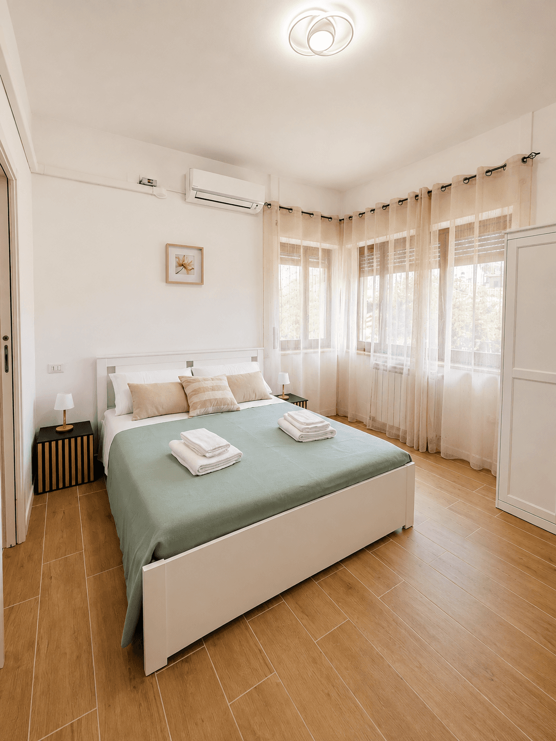 Camera con letto matrimoniale e biancheria verde salvia